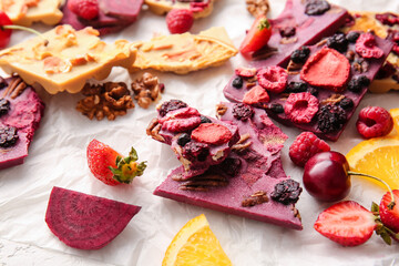 Handmade chocolate bars with fruits, berries and nuts on light background