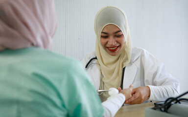 Young female muslim doctor cleaning patient's wrist using cotton swap with alcohol and preparing for a vaccine shot