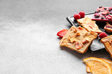 Handmade chocolate bars with fruits, berries and nuts on grey background