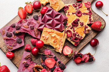 Handmade chocolate bars with fruits, berries and nuts on light background