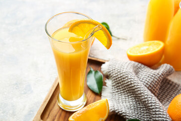 Board with glass of tasty orange juice on light background, closeup