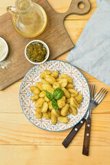 Plate with tasty gnocchi and pesto sauce on wooden background