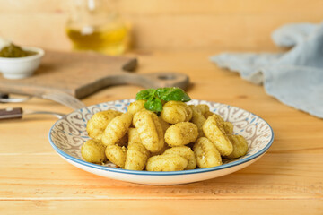 Plate with tasty pesto gnocchi on wooden background