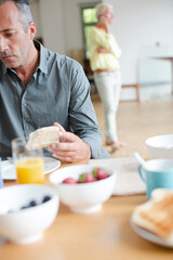 Older man using digital tablet at breakfast table