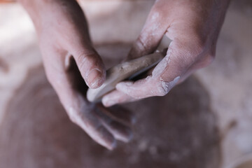 Fototapeta na wymiar Vertical photo of dirty hands working with clay