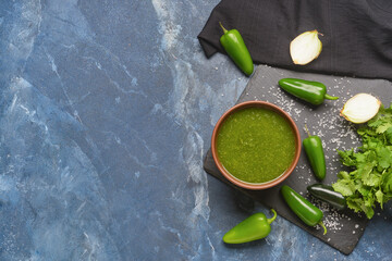 Bowl of Tomatillo Salsa Verde sauce and ingredients on color background