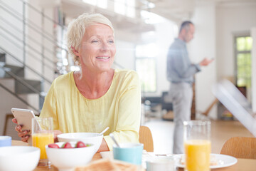 Older woman using digital tablet at breakfast table