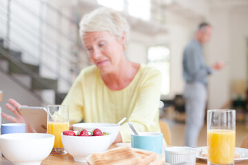 Fototapeta na wymiar Older woman using digital tablet at breakfast table
