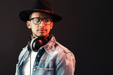 Young African American man portrait wearing headphones and hat and enjoy music over black Background