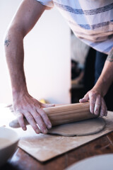 Man doing pottery at home. Close up of hands using clay roller