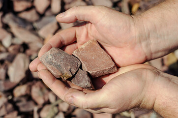 A man holds the Crimson Quartzite. Chipped rubble stone. Random