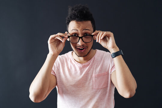 Emotional attractive male with opened mouth expresses great surprisment and frighteness, poses against black background, stares at camera. Unexpected shocking news and human reaction