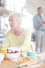 Older woman using digital tablet at breakfast table