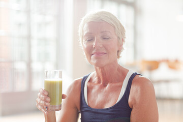 Older woman drinking juice on exercise mat