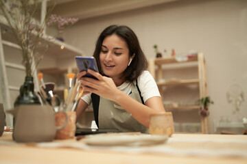 Happy craftswoman texting on smartphone
