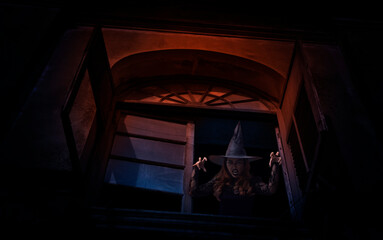 Scary halloween witch standing in old ancient window castle, Halloween mystery concept