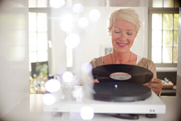 Older woman playing vinyl record on turntable