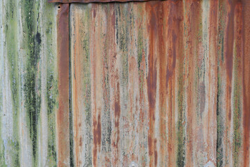 Old rusty corrugated metal background with red oxidisation and green mould