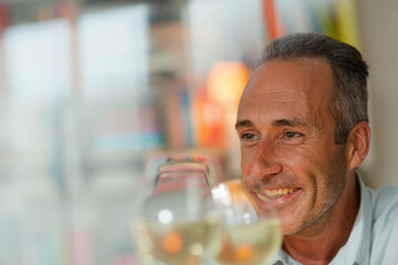 Older man drinking white wine at dinner