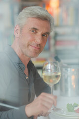Smiling older man toasting with white wine