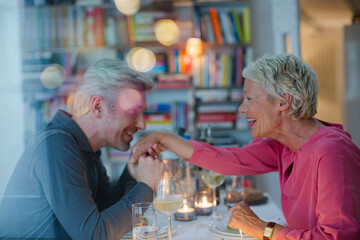 Older man kissing hand of wife at romantic dinner