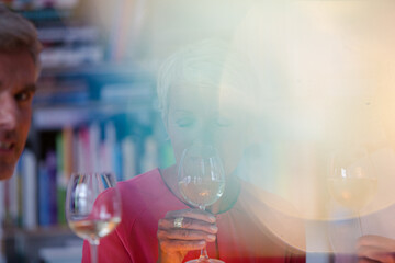 Older friends toasting each other with white wine