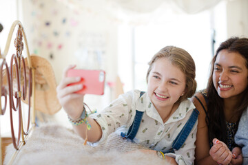 Three teenage girls taking selfie on bed in bedroom