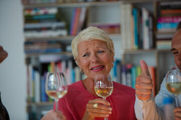 Older friends toasting each other with white wine