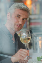 Smiling older man toasting with white wine