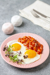 Continental breakfast - eggs, micro greens and beans in tomato sauce on a plate on the table. Healthy breakfast