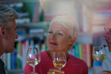 Older friends toasting each other with white wine