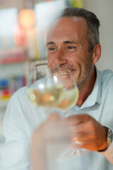 Older man drinking white wine at dinner