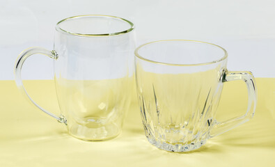 Different empty glass double hollow bottom cups on yellow surface