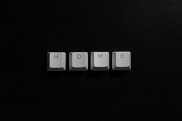 "Home" word on white keyboard keycaps on dark wood background.