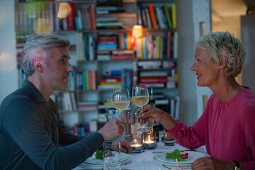 Older couple toasting each other at romantic dinner