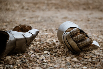 Pair of metallic gauntlets as part of knight equipment abandoned on the ground