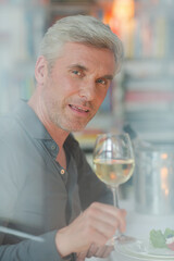 Smiling older man toasting with white wine