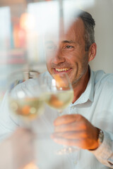 Older man drinking white wine at dinner