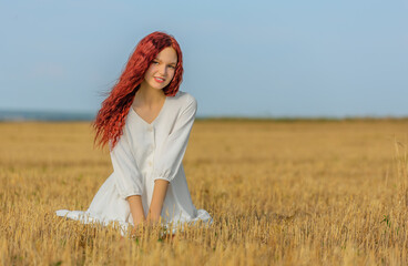 Teen girl sitting at meadow in hot summer day - 454051396