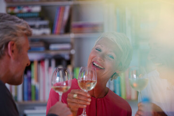 Older friends toasting each other with white wine