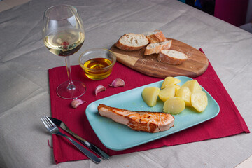 Escena gastronomía salmón con patatas, pan y vino blanco.