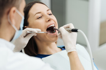 Overview of dental caries prevention. Girl at the dentist chair during a dental scaling procedure. Healthy Smile. - obrazy, fototapety, plakaty