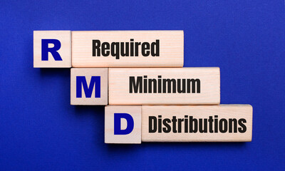 On a bright blue background, light wooden blocks and cubes with the text RMD Required Minimum Distributions