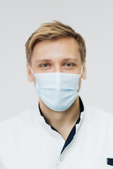 Portrait of a young male medical doctor wear sterile mask isolated on white background