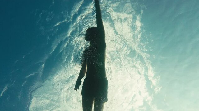 Ragazzo nuota nel mare in stile libero visto da sott'acqua