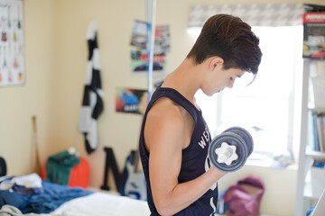 Fototapeta na wymiar Teenage boy exercising with dumbbell