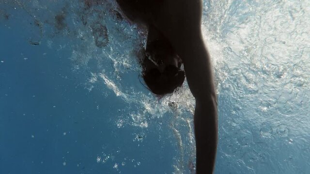 Ragazzo nuota nel mare in stile libero visto da sott'acqua