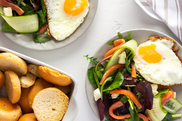 Fresh organic mesclun mix salad with cucumber, mozzarella and salmon, scrambled eggs and dry buns , delicious hearty breakfast