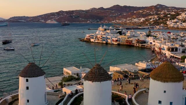 Aerial view through the famous windmills above Mykonos town, Cyclades, Greece, to the Little Venice district during summer sunset time