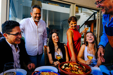 Cheerful men and woman with children enjoying dinner at home
